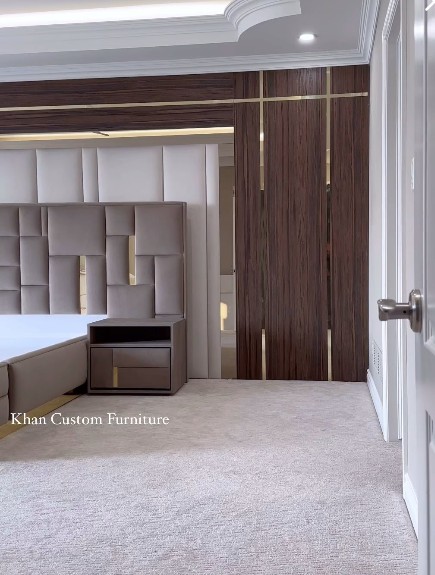Geometric padded headboard beside walnut wall panels with brass inlay